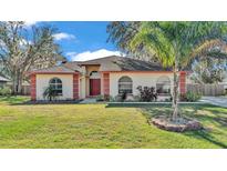 Single-story home with red accents and a lush green lawn at 1555 Archers Path, Lakeland, FL 33809