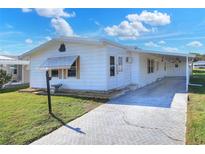 White single-wide manufactured home with covered carport and paved driveway at 6683 Briarhill Ne Dr, Winter Haven, FL 33881