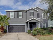Two-story house with gray siding, dark garage door, and landscaping at 1918 Wind Meadows Dr, Bartow, FL 33830