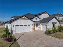 Two-story home with white siding, stone accents, and a three-car garage at 2728 Sunrise Landing Ln, Lakeland, FL 33812