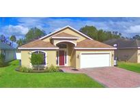 Charming single-story home with a red door, landscaped yard, and brick driveway at 3226 Oak Tree Ln, Winter Haven, FL 33884