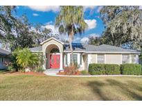 Charming single-story home with red double doors, lush landscaping, and a gray tiled roof at 6818 Hayter Drive, Lakeland, FL 33813