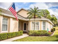 Tan house with palm trees, manicured lawn, and American flag at 7116 Lake Eaglebrooke Way, Lakeland, FL 33813