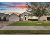 Single-story house with a two-car garage, landscaped lawn, and walkway at 332 Lake Mariana Way, Auburndale, FL 33823