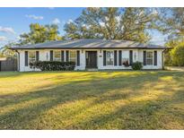 White brick ranch house with gray shutters, landscaping, and a large yard at 4409 Hallam Hill Ln, Lakeland, FL 33813