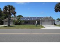 House exterior with solar panels, double garage, and palm trees at 806 South St, New Smyrna Beach, Fl 32168, FL 32168