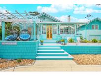 Charming bungalow with teal exterior, welcoming porch, and landscaped yard at 412 S Peninsula Ave, New Smyrna Beach, FL 32169