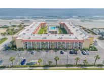 Aerial view of an oceanfront building with parking and pool at 3801 S Atlantic Ave # 307, New Smyrna Beach, FL 32169