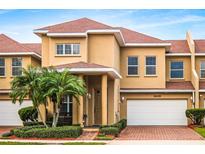 Tan two-story townhome with red tile roof, two-car garage, and palm trees at 3608 Romea Cir, New Smyrna Beach, FL 32168