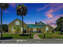 Charming yellow house with green roof, walkway, and lush landscaping at 886 Matthews Ave, New Smyrna Beach, FL 32169