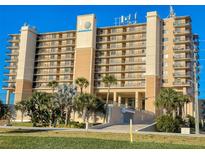 Tan multi-story building with balconies and palm trees at 4139 S Atlantic Ave # B608, New Smyrna Beach, FL 32169