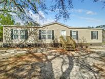 Tan mobile home with brown brick skirting and a wooden staircase at 31537 Lakeside Dr, Deland, FL 32720