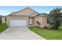 Tan house with a white garage door and brick paved driveway at 165 Captain Hook Way, Davenport, FL 33837