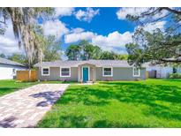 Newly renovated home with a teal front door, paved driveway, and lush lawn at 278 Debary Dr, Debary, FL 32713