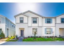 Two-story townhome with gray siding, dark gray door, and landscaped lawn at 8916 Sydney Ave, Kissimmee, FL 34747