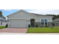 One-story house with light beige siding, a gray roof, and a two-car garage at 964 Avenal Ln, Davenport, FL 33837