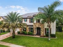 Two-story house with stone accents and solar panels at 15465 Heron Hideaway Cir, Winter Garden, FL 34787