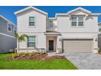 Two-story house with beige siding, gray garage door, and well-manicured lawn at 2126 Lelani Cir, Davenport, FL 33897