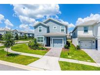 Two-story house with gray exterior, two car garage, and landscaping at 1592 Tempo Ln, Davenport, FL 33896