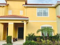 Bright yellow two-story home with landscaping and double doors at 8953 California Palm Rd, Kissimmee, FL 34747