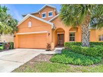 Two-story house with orange exterior and landscaping at 742 Orange Cosmos Blvd, Davenport, FL 33837