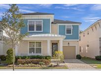 Two-story light blue home with white accents and a front porch at 1909 Tropical Palms Cir, Kissimmee, FL 34747