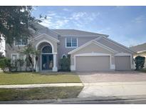 Two-story house with a three-car garage and landscaped lawn at 2887 Sweetspire Cir, Kissimmee, FL 34746