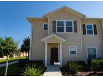 Two-story townhome with light beige exterior and dark brown door at 8947 Shine Dr, Kissimmee, FL 34747