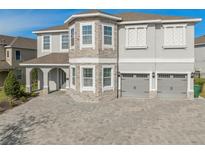 Two-story house with stone accents and a three-car garage at 7713 Graben St, Kissimmee, FL 34747