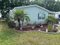 Light green mobile home with landscaped yard and palm trees at 263 Sue Ave, Davenport, FL 33897