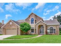 Two-story brick home with a landscaped lawn and attached garage at 2111 Turnberry Dr, Oviedo, FL 32765