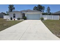 Modern house exterior with a light-colored facade, attached garage, and landscaped lawn at 66 Orchid Ct, Kissimmee, FL 34759