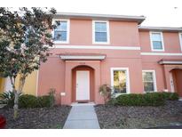 Two-story townhome with peach-colored exterior, landscaping, and walkway at 3004 Red Ginger Rd, Kissimmee, FL 34747