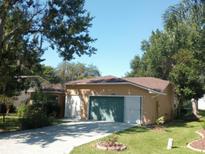Tan house with a two-car garage and a well-maintained lawn at 32525 Oak Park Dr, Leesburg, FL 34748