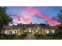 Elegant two-story home with stone accents and a dramatic sunset backdrop at 6845 Valhalla Way, Windermere, FL 34786