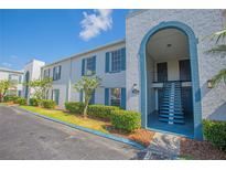 Building exterior featuring a blue and white color scheme, landscaping, and a stairwell at 1048 Plantation Dr # E-9, Kissimmee, FL 34741