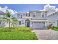 Two-story house with gray exterior, paver driveway, and landscaping at 1549 Maidstone Ct, Davenport, FL 33896