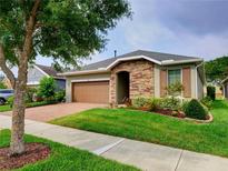 One-story home with stone accents, brown garage door, and landscaped lawn at 251 Silver Maple Rd, Groveland, FL 34736