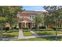 Two-story townhome with orange exterior and landscaping at 14090 Avenue Of The Groves, Winter Garden, FL 34787