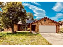 Brick house with a two-car garage and solar panels on the roof at 2037 Apricot Dr, Deltona, FL 32725