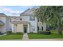 Two-story townhome with light beige siding and landscaping at 200 Southern Pecan Cir # 105, Winter Garden, FL 34787