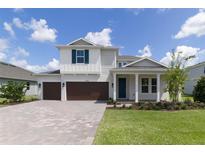 Two-story home with brown double garage doors and a landscaped front yard at 2993 Water Clover Ct, Apopka, FL 32712