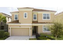 Two-story house with tan walls, a brown roof, and a two-car garage at 5300 Oakbourne Ave, Davenport, FL 33837