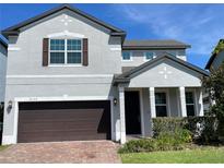 Two-story house with gray siding, brown garage door, and landscaping at 14154 Dove Hollow Dr, Orlando, FL 32824