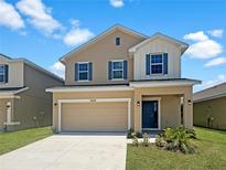 Tan two-story house with a two-car garage and landscaping at 3654 Sagefield Dr, St Cloud, FL 34773