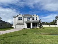 Two-story house with light gray siding, gray roof, and landscaping at 128 Lake Dr, Oviedo, FL 32765