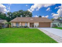 Ranch style home with brown roof, attached garage, and well-maintained lawn at 7628 Eldorado Pl, Orlando, FL 32818