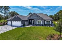 Single-Gathering home with stone and gray siding, three car garage at 17694 Sw 61St Lane Rd, Dunnellon, FL 34432