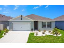 Charming one-story home with gray exterior, white garage door, and landscaping at 1157 Torrente Ln, Haines City, FL 33844