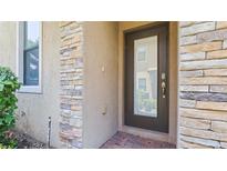 Modern dark brown front door entry with stone accents at 8940 Azalea Sands Ln # 8940, Davenport, FL 33896